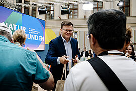 Bundesumweltminister Carsten Schneider verteilt Gewinne an die Besucherinnen und Besucher.