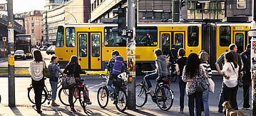 Fußgänger warten auf grünes Licht am Alexanderplatz, eine Straßenbahn fährt vorbei.