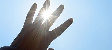 Hand schützend vor die Sonne gehalten.