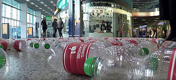 Flaschen liegen auf dem Boden. Auf dem Etikett steht "Einwegflaschen" und das Symbol "Daumen nach untern"