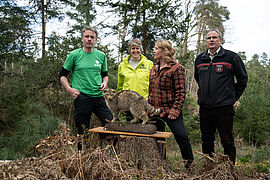 Steffi Lemke mit drei Fachleuten und der Wildkatze (Taxidermie) im Vordergrund im Wald