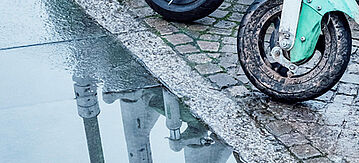 Reflexionen von E-Scooter in einer Pfütze