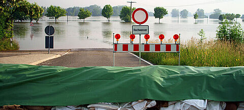 Der Blick von einer Straßensperrung auf ein vom Hochwasser betroffenes Gebiet.