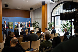 Journalistinnen und Journalisten bei der Pressekoneferezn zur Klimabilanz 2025, im Hintergrund Carsten Schneider und Dirk Messner
