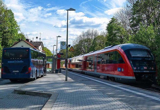 Eine Bahn und ein Bus an einem Bahnhof