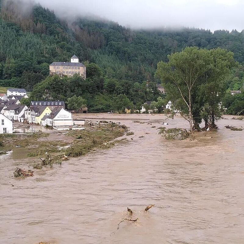 Aufnahme des überschwemmten Ahrtals mit Hochwasser und überfluteten Bäumen und Häusern.