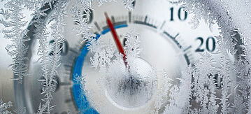 Thermometer hinter Glas. Frost auf dem Fenster im Fokus.