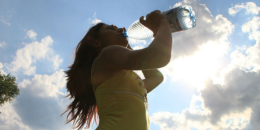Eine Person trinkt Wasser im Sommer