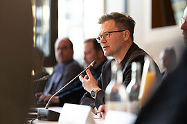 Carsten Schneider am Mikrofon im Konferenzraum