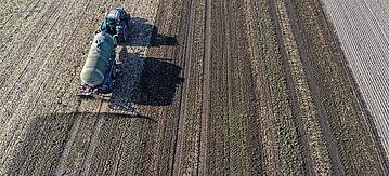 Traktor bringt Gülle auf einem Feld auf.