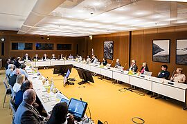 Blick in den Diskussionsraum mit allen Teilnehmenden am Tisch. 