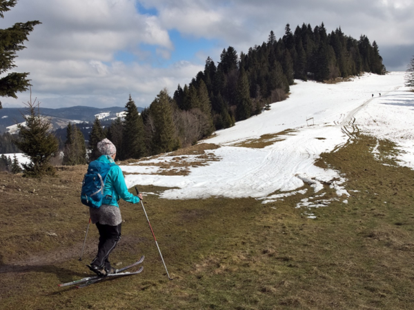 Eine Skifahrerin auf einer wenig beschneiten Skipiste