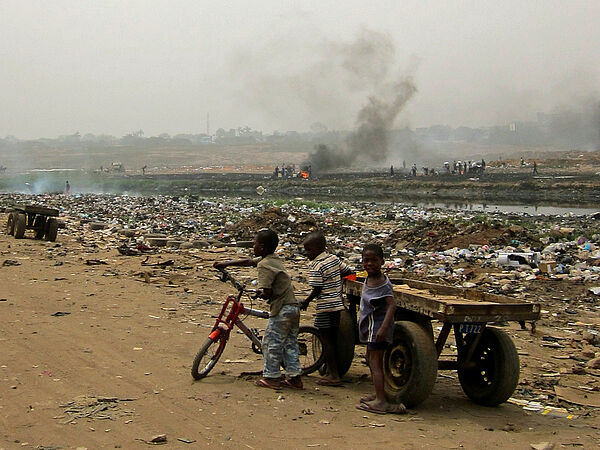 Müllkippe für Elektroschrott, davor Kinder