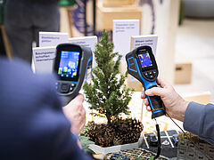 Zwei Peronen scannen eine Pflanze mit einer Wärmebildkamera.