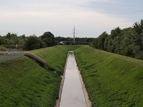 Ein begradigter Fluss in Beton gefasst, daneben grün