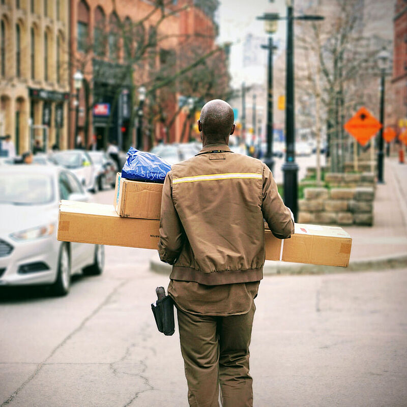 Ein Paketbote trägt Pakete zu einer Haustür