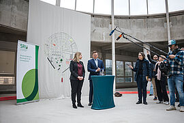 Carsten Schneider steht neben Bundesbauministerin Verena Hubertz am Rednerpult. 