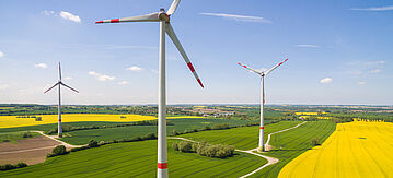 Windturbinen auf schönen landwirtschaftlichen Feldern unter blauem Himmel