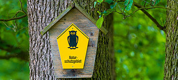 Schild für Naturschutzgebiet: Gelber Hintergrund mit dem Bild einer Eule