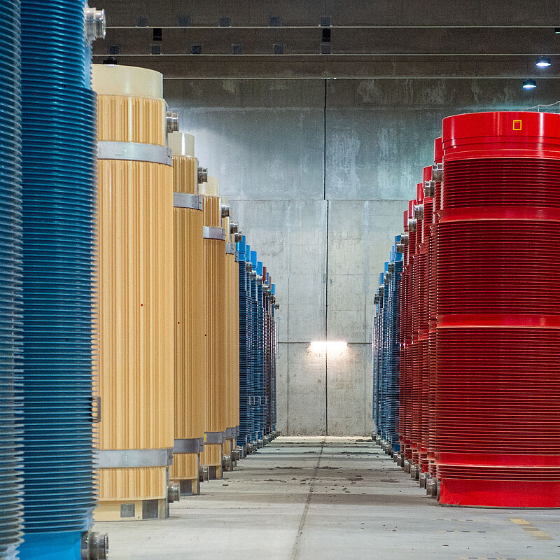 Lagerhalle mit gelben, roten und blauen Castorbehältern.