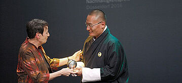 Barbara Hendricks überreicht vor dunklem Hintergrund einen Preis an den Premierminister von Bhutan