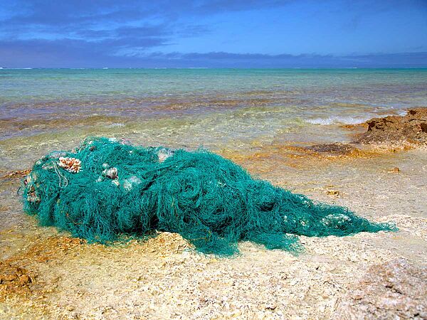 Ein an Land gespültes türkis farbenes Fischernetz an der Küste