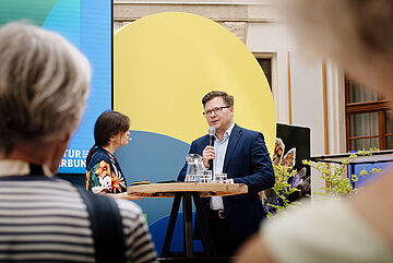 Moderatorin Nadine Kreutzer mit Bundesumweltminister Carsten Schneider. Weitere Informationen siehe Bildunterschrift