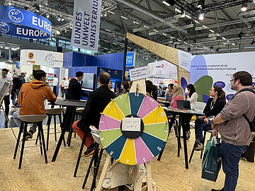 Messestand des BMUKN: Besucher und ein Glücksrad