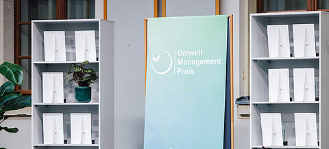 Aufsteller zum Umweltmanagementpreis zwischen 2 Regalen