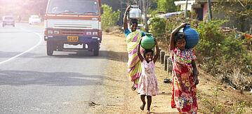 Landländisch indische Frauen tragen Wasser auf dem Kopf in traditionellen Töpfen