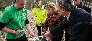 Steffi Lemke schaut sich die Waldkarte mit den Förstern an