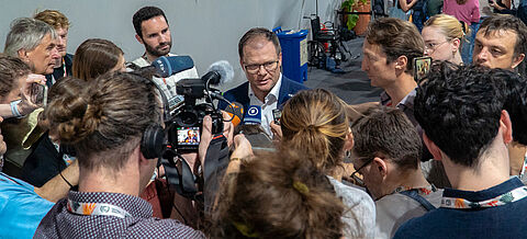 Carsten Schneider umringt von Medienvertretern.