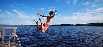 Sprung eines jungen Mannes vom Steg in einen See.