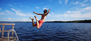 Sprung eines jungen Mannes vom Steg in einen See.