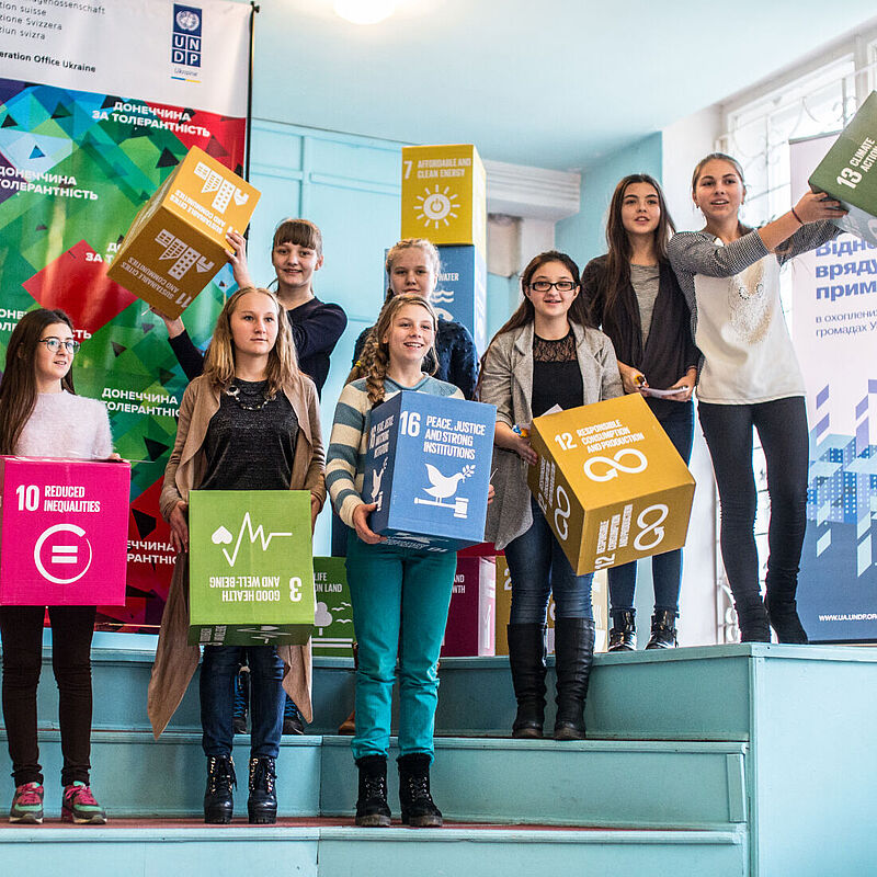 Kinder halten Würfel mit den Symbolen der verschiedenen SDGs.