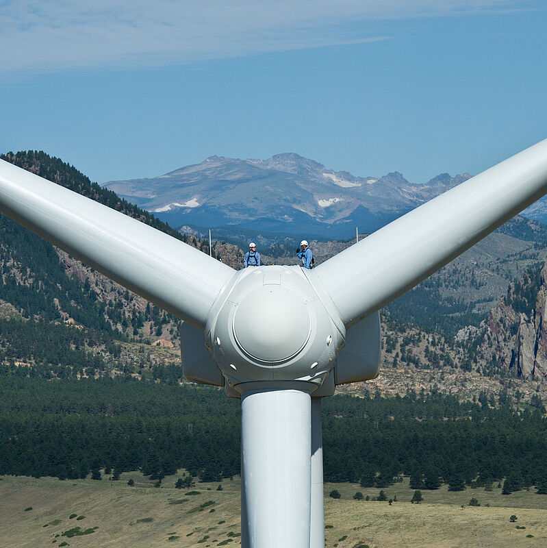 Zwei Personen arbeiten an einer Windkraftanlage. 