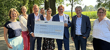 Personen halten riesigen Scheck in die Kamera