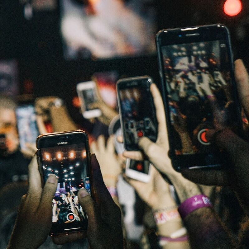 Konzertbesucher halten Handys hoch, um die Bühne zu filmen.