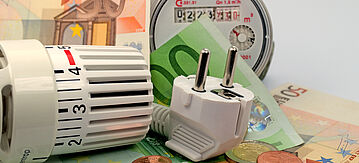 Nebenkostenabrechnung: Heizungsregler, Elektrostecker, Wasserableser auf Geldscheinen