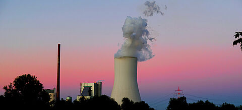 Ein Kohlekraftwerk mit dampfendem Kühlturm im Sonnenuntergang