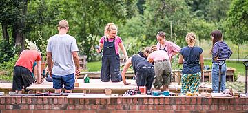 Bauworkshop: Gruppe Jugendlicher mit Werkzeugen und Holzarbeiten draußen.