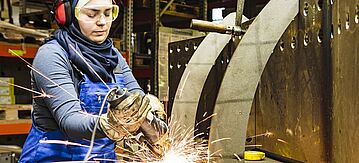 Auszubildende arbeitet mit einem Winkelschleifer