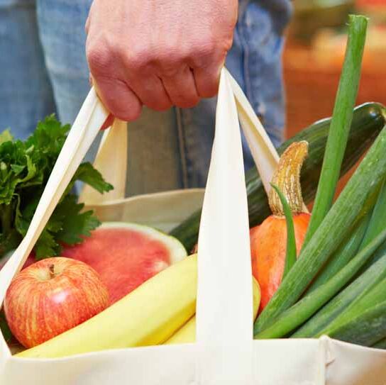 Mann trägt volle Tasche mit Obst und Gemüse im Supermarkt
