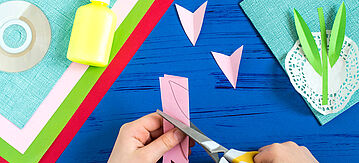 Ein Kind schneidet und bastelt Tulpen aus Papier.