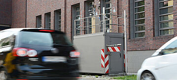 Autos fahren in der Stadt an einer Messstation vorbei