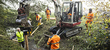 Bauarbeiten an einem Bach mit einem Bagger
