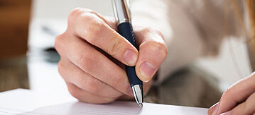 Augeklappter Aktenordner, neben dem ein weiß blauer Kugleschreiber liegt