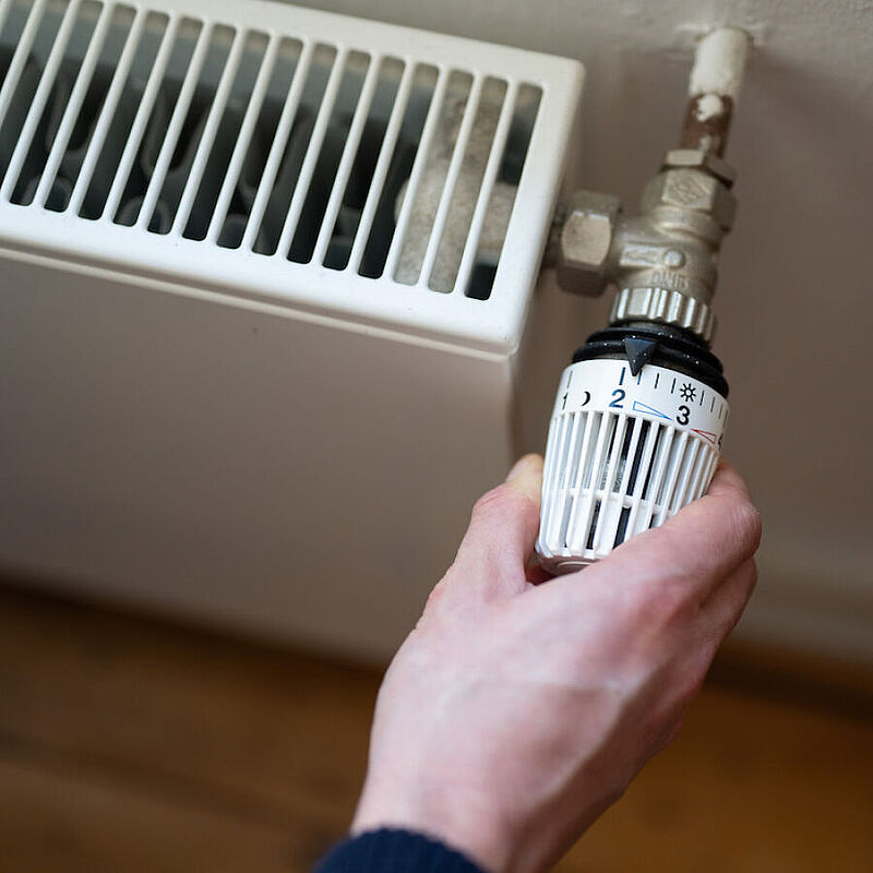 Eine Hand an einem Heizungsregler