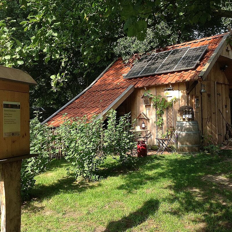 Gartenhütte mit Solarpanels, davor ein Insektenhaus