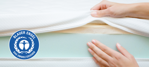 Hand zeigt auf die Schichten einer Matratze.